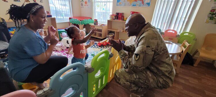 Command Sgt. Maj. Shelly Jenkins, Fort Drum garrison senior enlisted adviser, entertains a toddler during a routine inspection of a Family Child Care home. (Photo by Mike Strasser, Fort Drum Garrison Public Affairs)